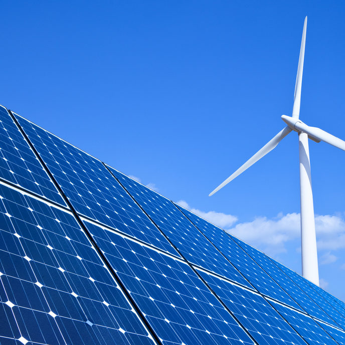 Solar panels and wind turbine against blue sky